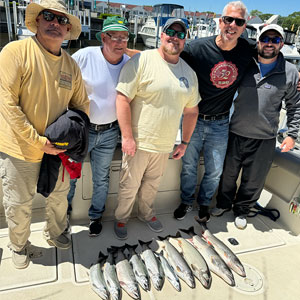 Group of 5 clients posing on the charter boat with the lake fish they caught